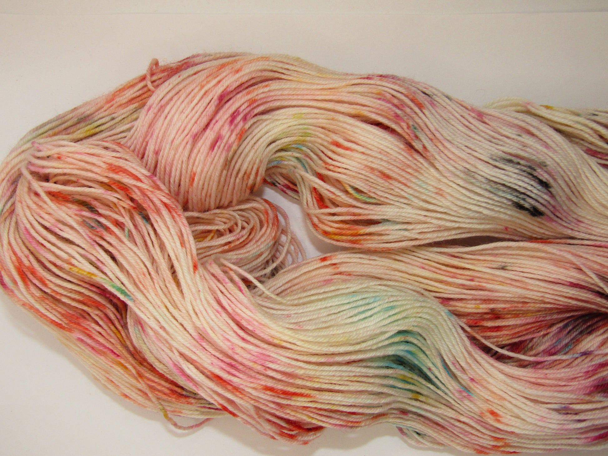 Hand-Dyed Yarn Confetti with speckles in blue, orange, red, pink, purple, black, and yellow.
