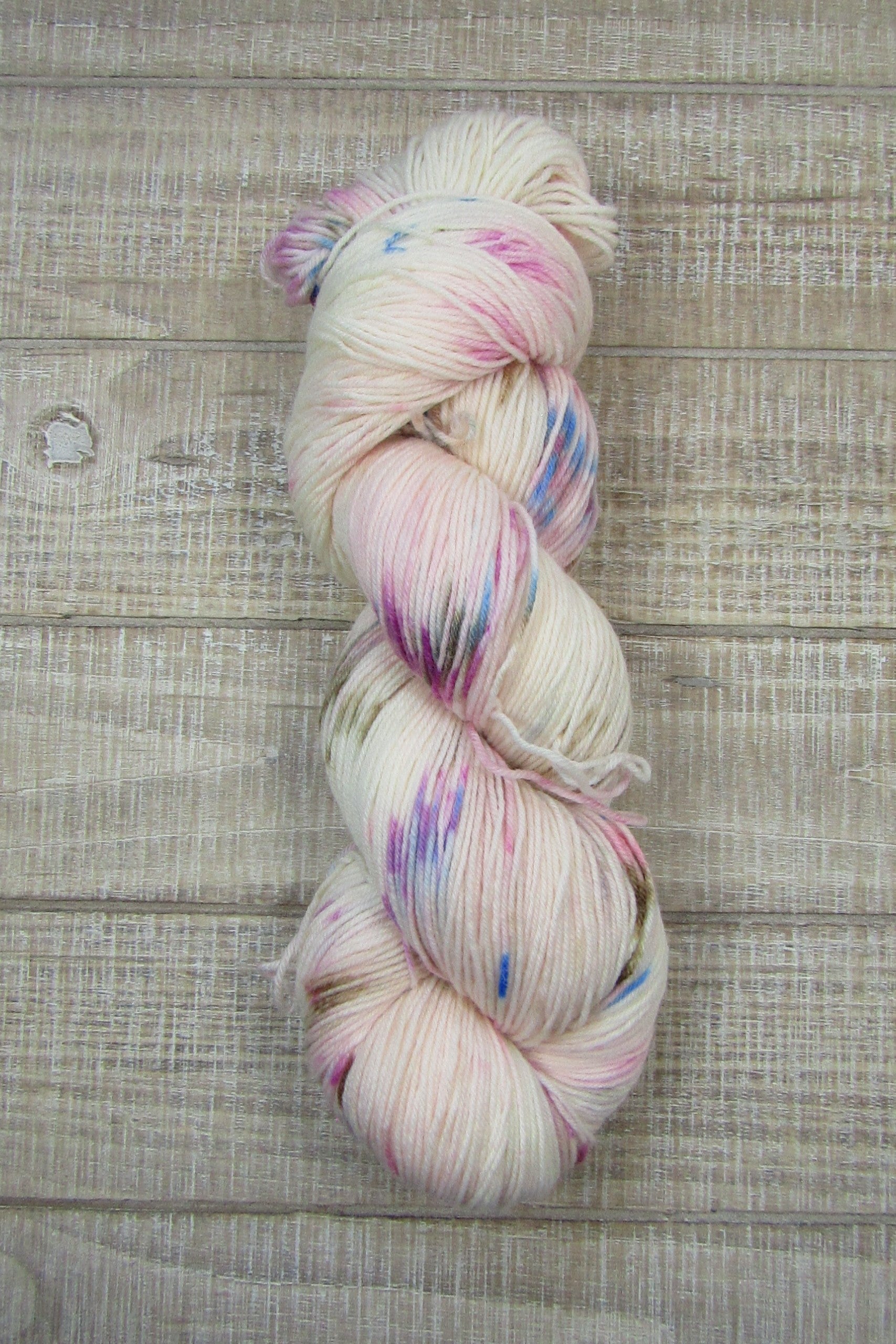 Hand-Dyed Yarn speckled with blue, chestnut, berry crush, and pink.