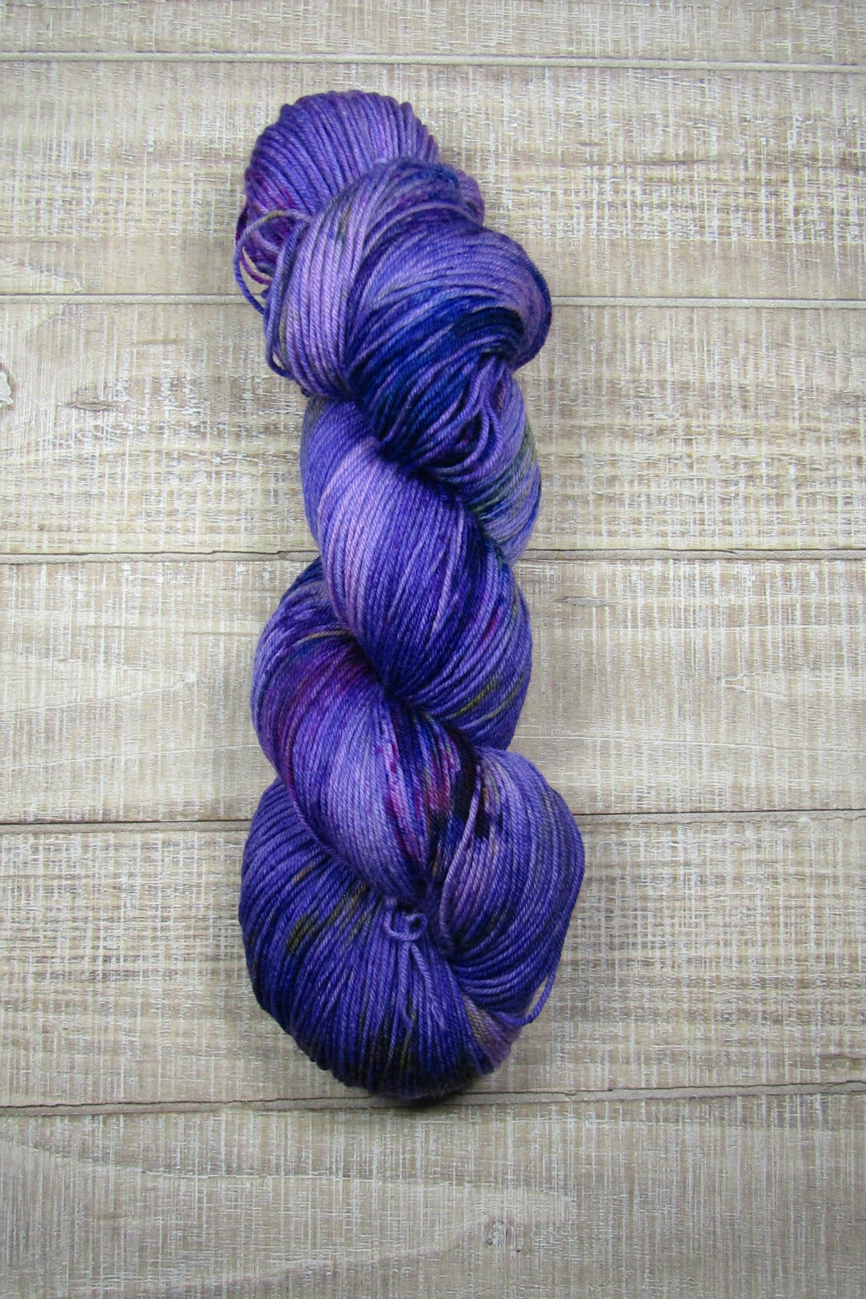 Hand-Dyed Yarn Galileo in a color of purple with areas of blue, yellow, brown, purple, and fuschia.