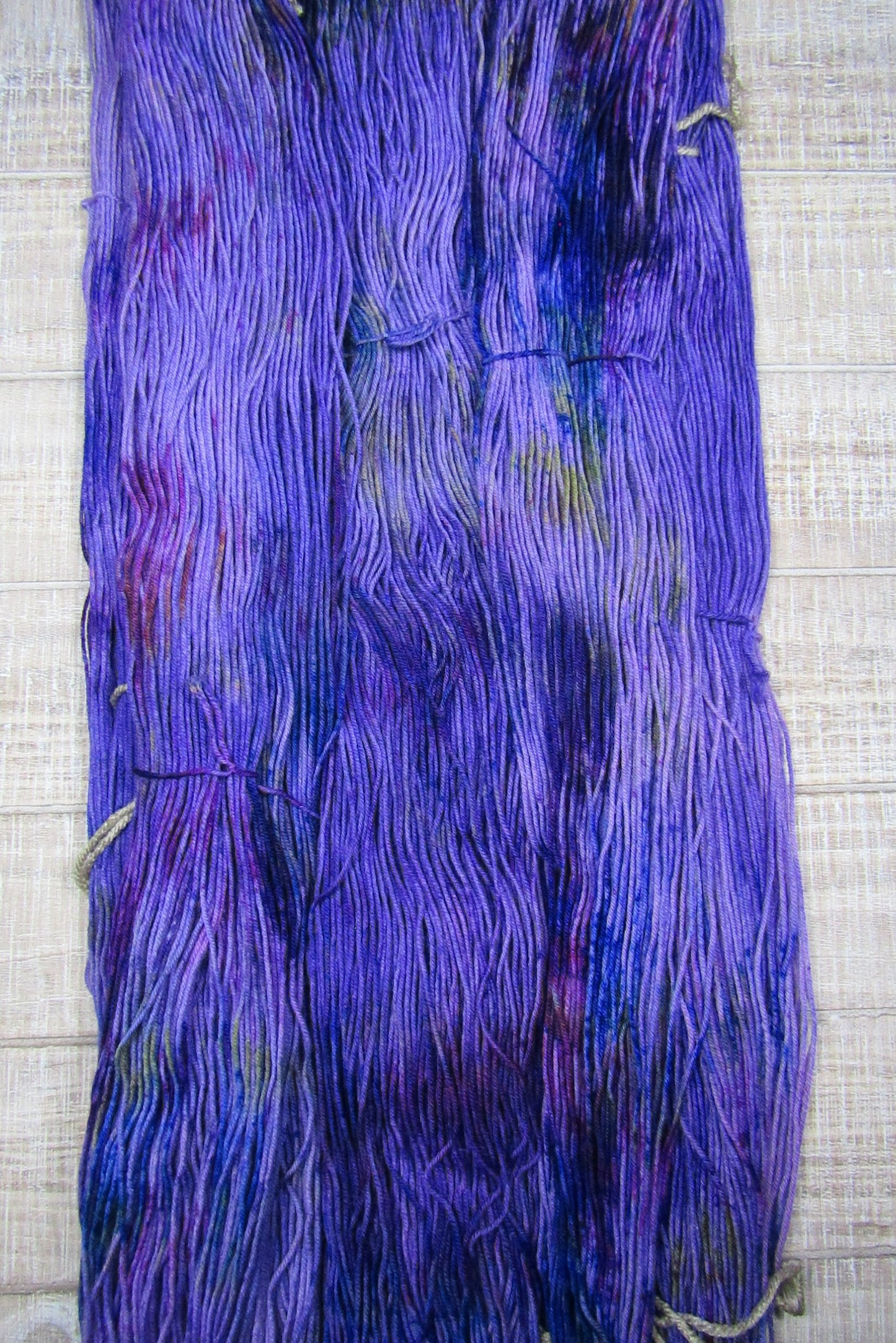 Hand-Dyed Yarn Galileo in a color of purple with areas of blue, yellow, brown, purple, and fuschia.