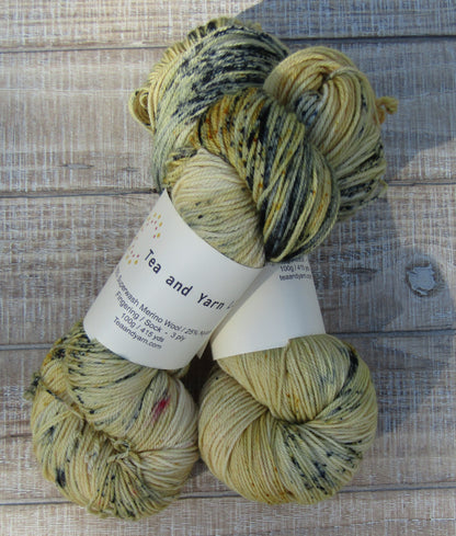 Hand-Dyed Yarn Sawyer Single Skein of yarn in a main color of golden straw with speckles of blue, red and mustard.