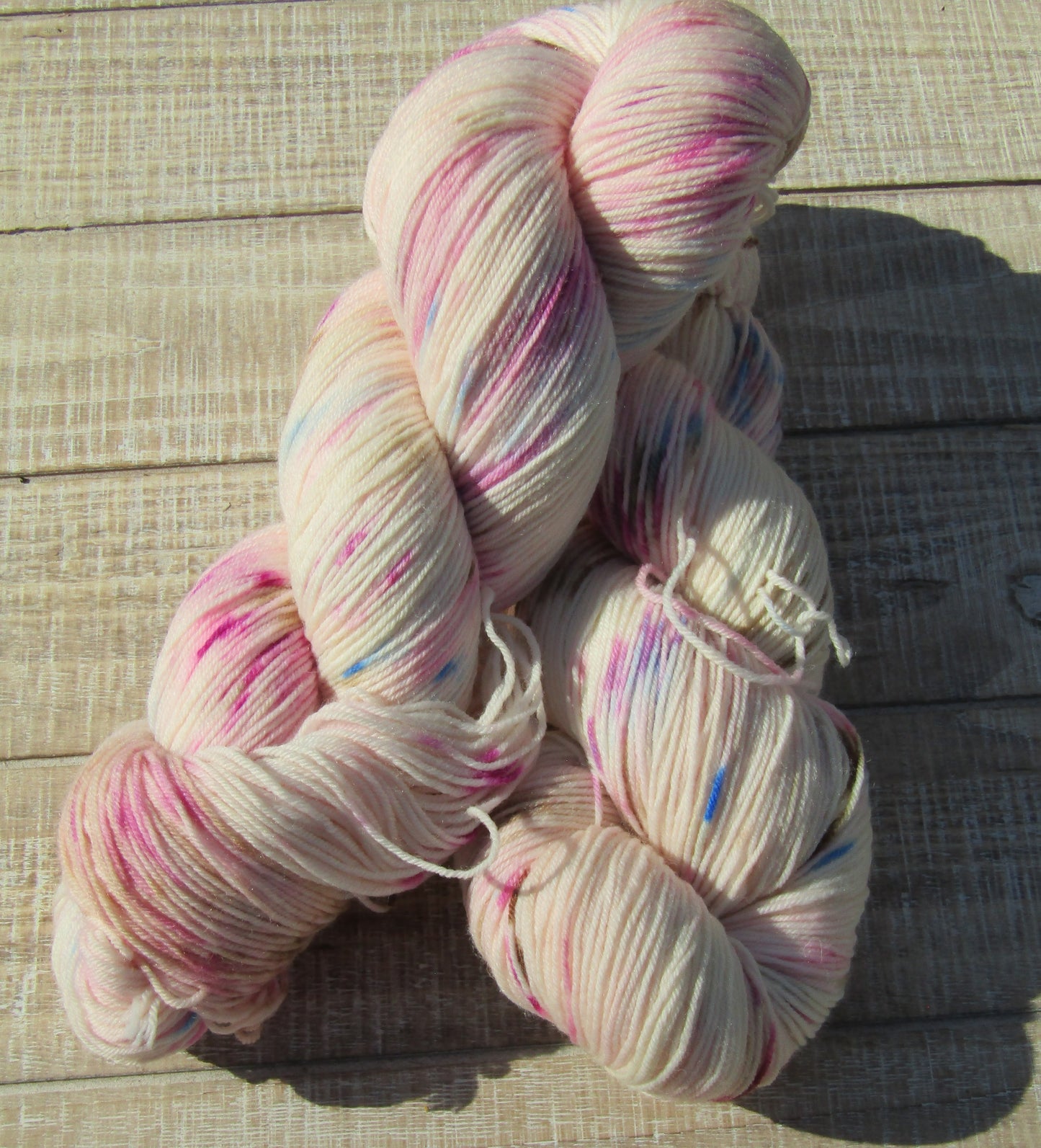 Hand-Dyed Yarn speckled with blue, chestnut, berry crush, and pink.